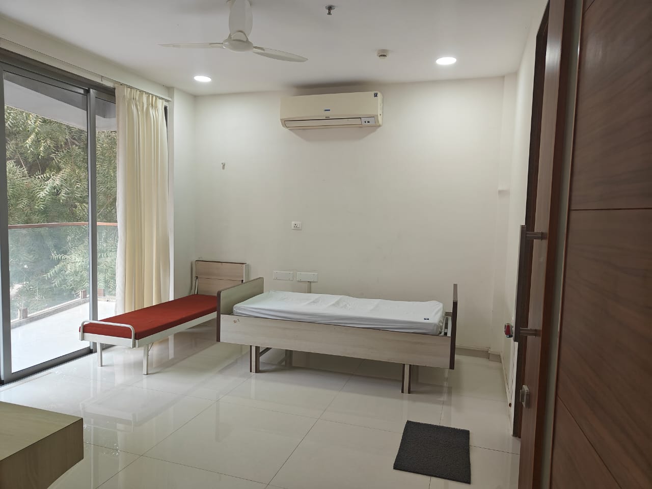 Patient suite with hospital bed, AC and balcony view.