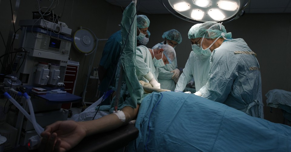 British doctor Christophe Bulstrode (C) and Palestinian surgeons from the Gaza Strip perform a surgery on a patient at Nasser Hospital in Khan Yunis, southern Gaza, on December 15, 2009. French medical non governmental organization Medecins du Monde, led by senior surgeon Dr. Bulstrode arrived in Gaza for an one-week training session, aiming at upgrading the knowledge of some ten orthopedic surgeons from Gaza in the field of war and trauma orthopedic medicine. AFP PHOTO/ SAID KHATIB (Photo credit should read SAID KHATIB/AFP/Getty Images)